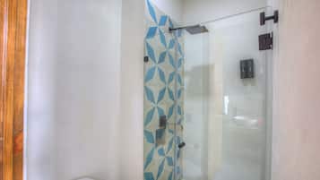 Een badkamer met een douchecabine van glas, een toilet en een wastafel.