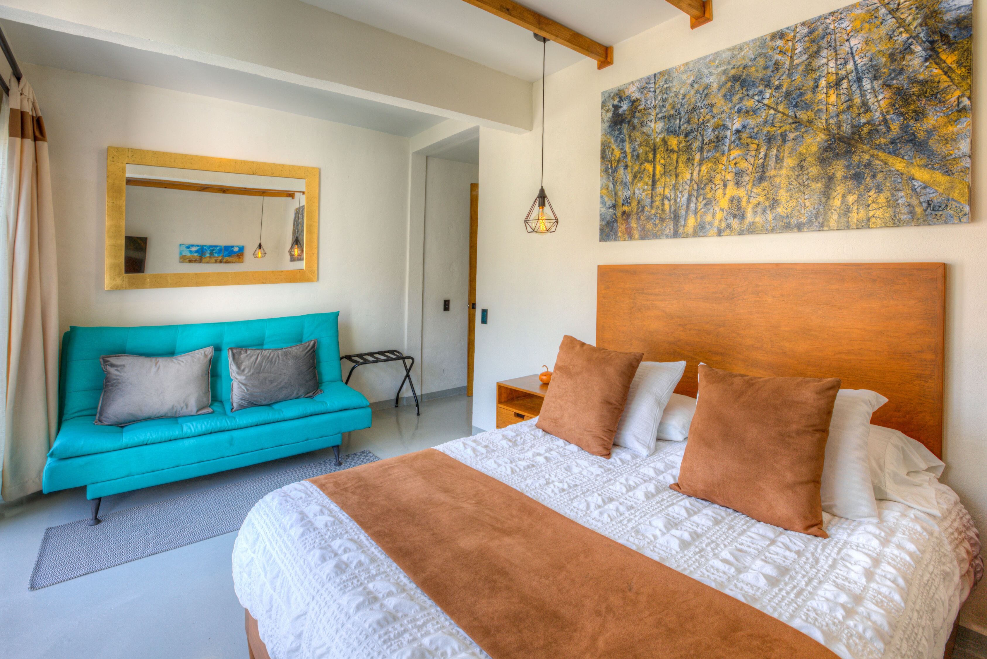 A bedroom with a large bed, a blue sofa, and a wooden headboard.