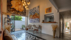 A spacious lobby with a geometric tile floor, a large mountain painting, and a seating area with chairs.