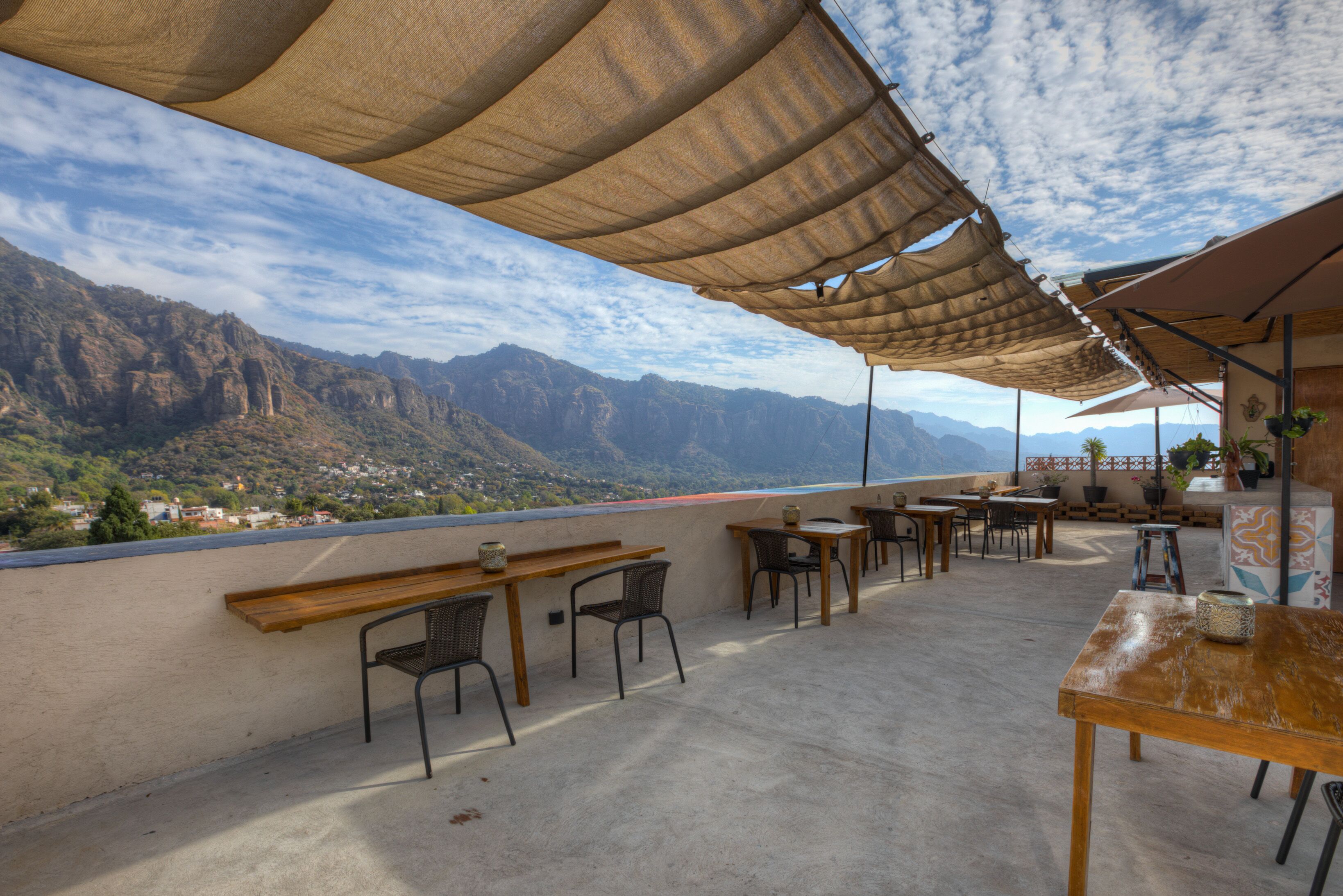Una terraza al aire libre con mesas y sillas, con vistas a un paisaje montañoso.