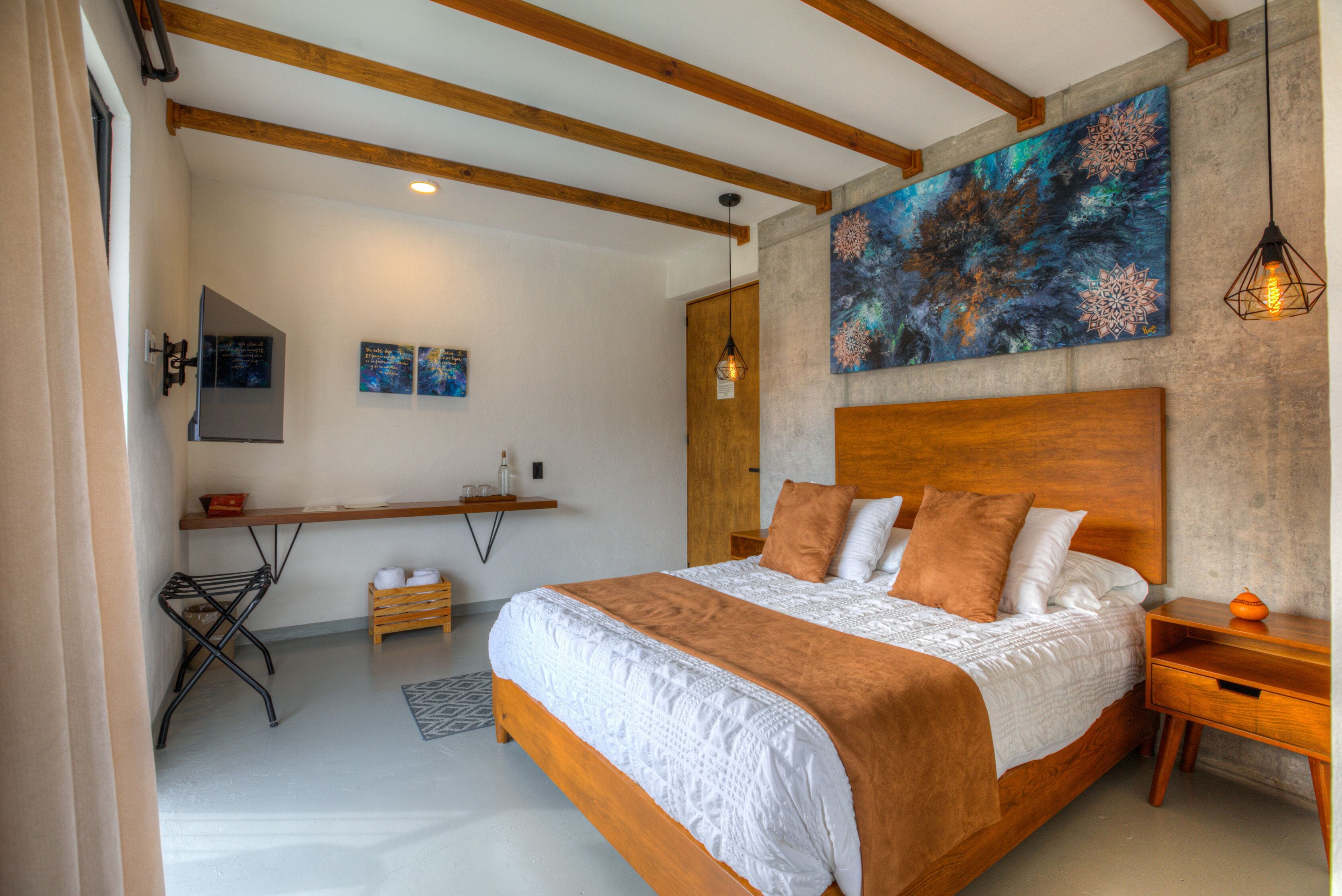 A modern bedroom with a large bed, wooden headboard, and a painting on the wall.