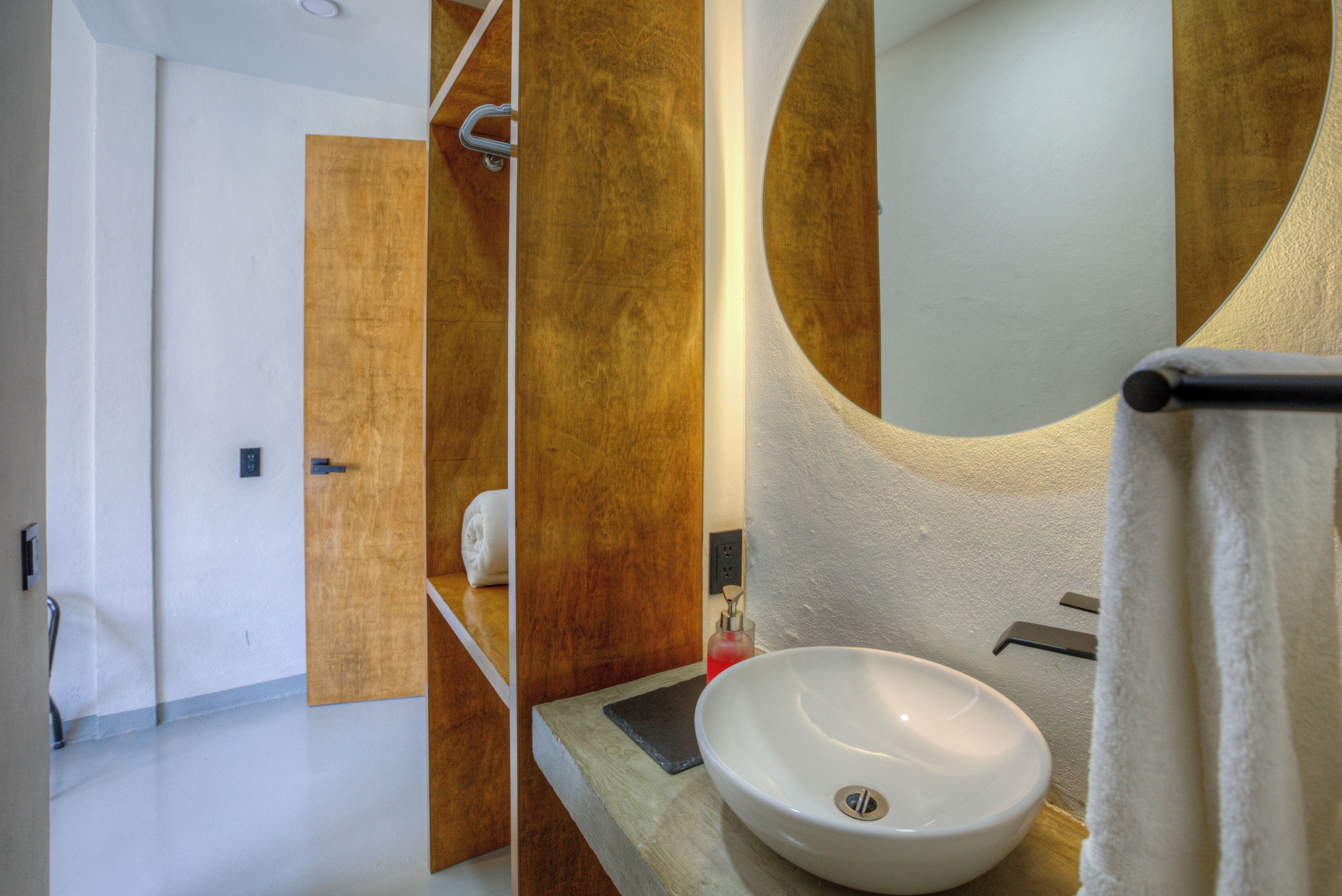 A bathroom with a wooden vanity, a white sink, and a large mirror.