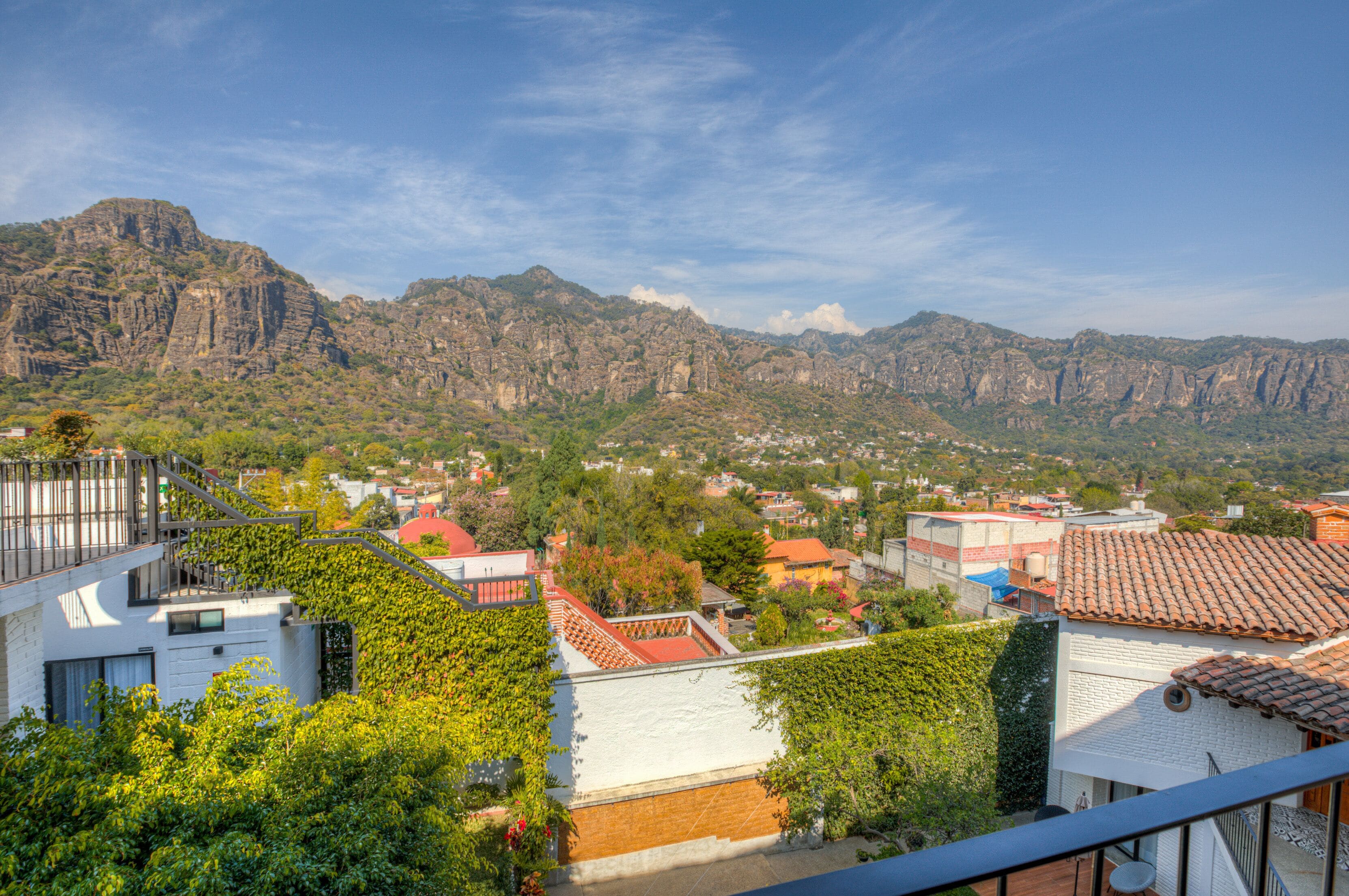 A residential area with houses, a mountain backdrop, and a balcony with a view.