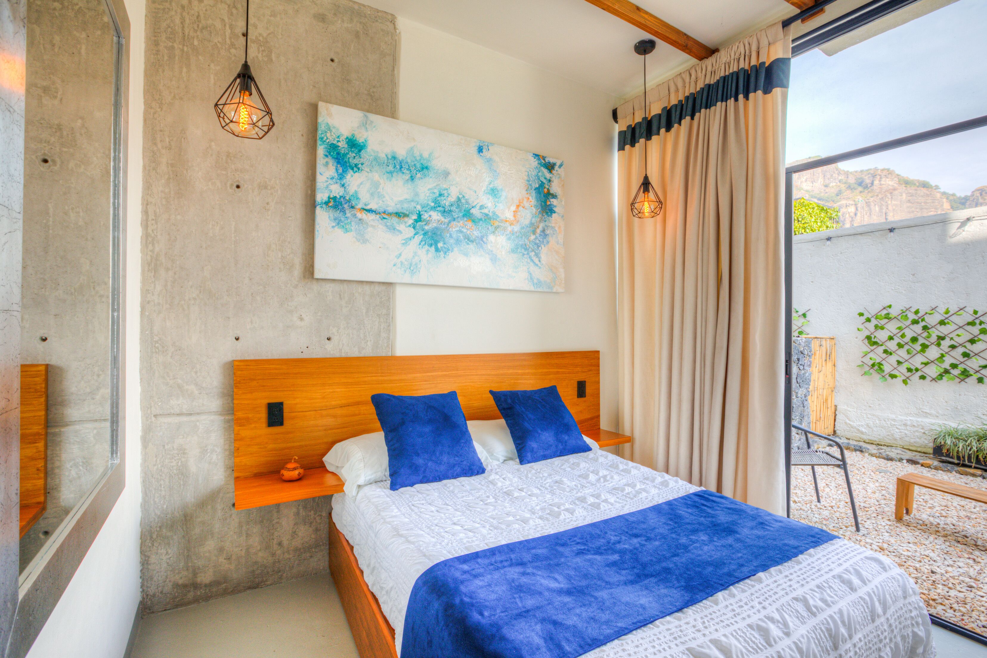 Un dormitorio moderno con una cama grande, una pared de concreto y vistas al exterior.