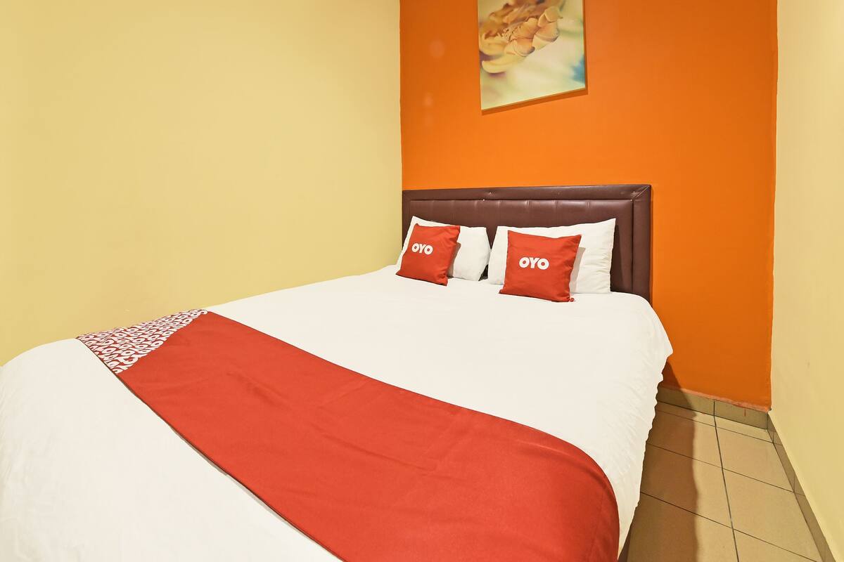 Une chambre d’hôtel avec un lit, une tête de lit et un tableau au mur.