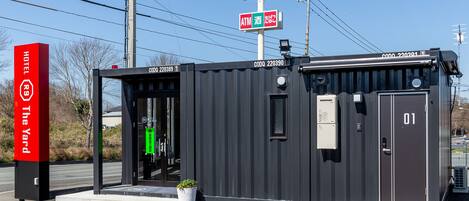 A compact, modern building with a black exterior, a visible entrance, and a small window.