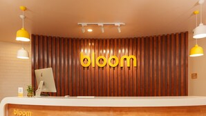 Un mostrador de recepción con un fondo de madera y la palabra “bloom” en letras amarillas.