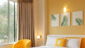 Una habitación de hotel con cama, una silla, una mesa y una ventana con cortinas.