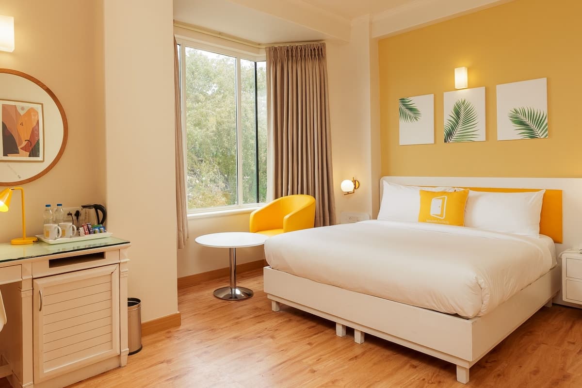 A hotel room with a bed, a desk, a chair, and a window with curtains.