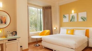 A hotel room with a bed, a desk, a chair, and a window with curtains.
