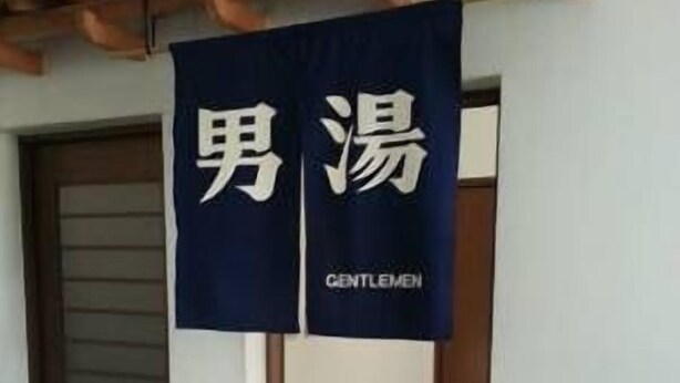 Un pasillo con un estandarte azul oscuro colgado en la pared que muestra la palabra 'GENTLEMEN'.