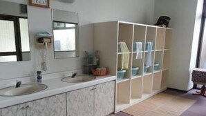 Un baño con dos lavamanos, un espejo, un armario de aseo y una zona de ducha.