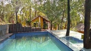 A rectangular swimming pool with clear blue water, surrounded by a wooden deck and trees.
