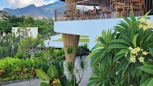 A hotel with a balcony featuring outdoor seating and lush greenery. - Sumberkima Resort (Pemuteran)
