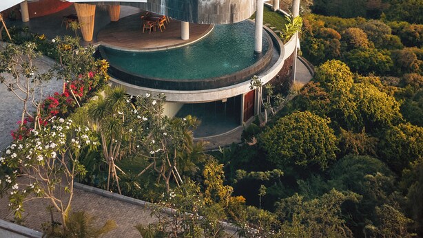 A multi-level resort with a central infinity pool, outdoor seating, and lush surrounding vegetation. - Sumberkima Resort (Pemuteran)