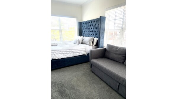 Relax in this serene bedroom with a large bed and comfortable sofa.