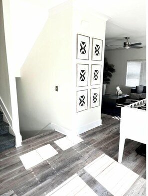 Staircase leads to an upper level, with a foosball table and abstract art on the wall.