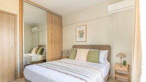 A bedroom with a large bed, a bedside table with a lamp, a small plant, and a wall-mounted air conditioner. - Superior 3BR Apartment in Chalandri (Chalandri)