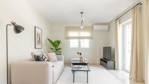A modern living room with a sofa, a coffee table, a TV, and a large window with curtains. - Superior 3BR Apartment in Chalandri (Chalandri)