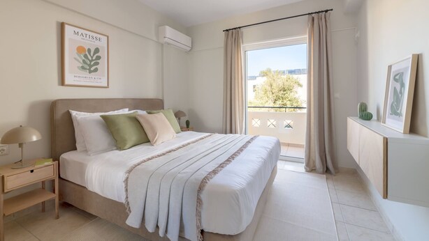 A modern bedroom with a large bed, a bedside table, a lamp, a framed artwork on the wall, and a view of the outdoors through a balcony. - Superior 3BR Apartment in Chalandri (Chalandri)