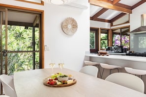 Enjoy meals in the kitchen with a central island, stove, and coffee machine, adjacent to a dining area with a large table for two.