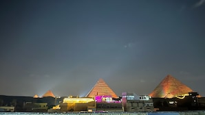A nighttime view of the pyramids with illuminated structures in the foreground. - Falcon pyramids inn (Giza)