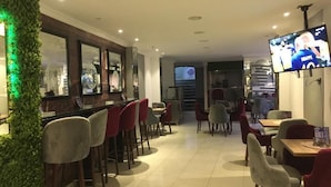 A restaurant with a bar area, multiple seating options, and a television screen. - Falcon pyramids inn (Giza)