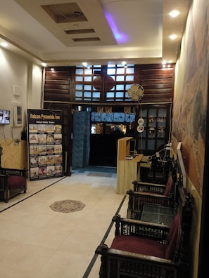 A hotel lobby with a reception desk, a signboard for hotel tours, and traditional wooden furniture.