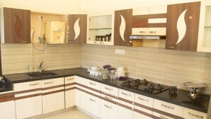 A kitchen with a black countertop, white cabinets, and a stainless steel range hood. - White Haven Luxury Villa (Kilvelur)