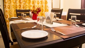 A dining table set with plates, cutlery, and a vase of flowers. - White Haven Luxury Villa (Kilvelur)