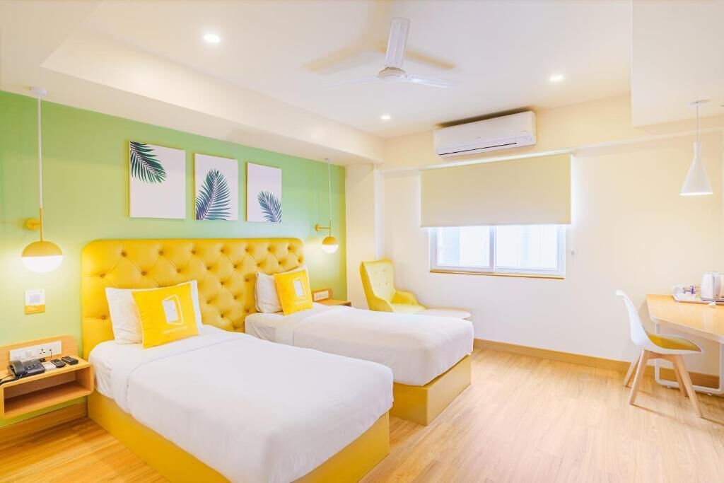 A hotel room with two beds, a desk, a chair, and a window.