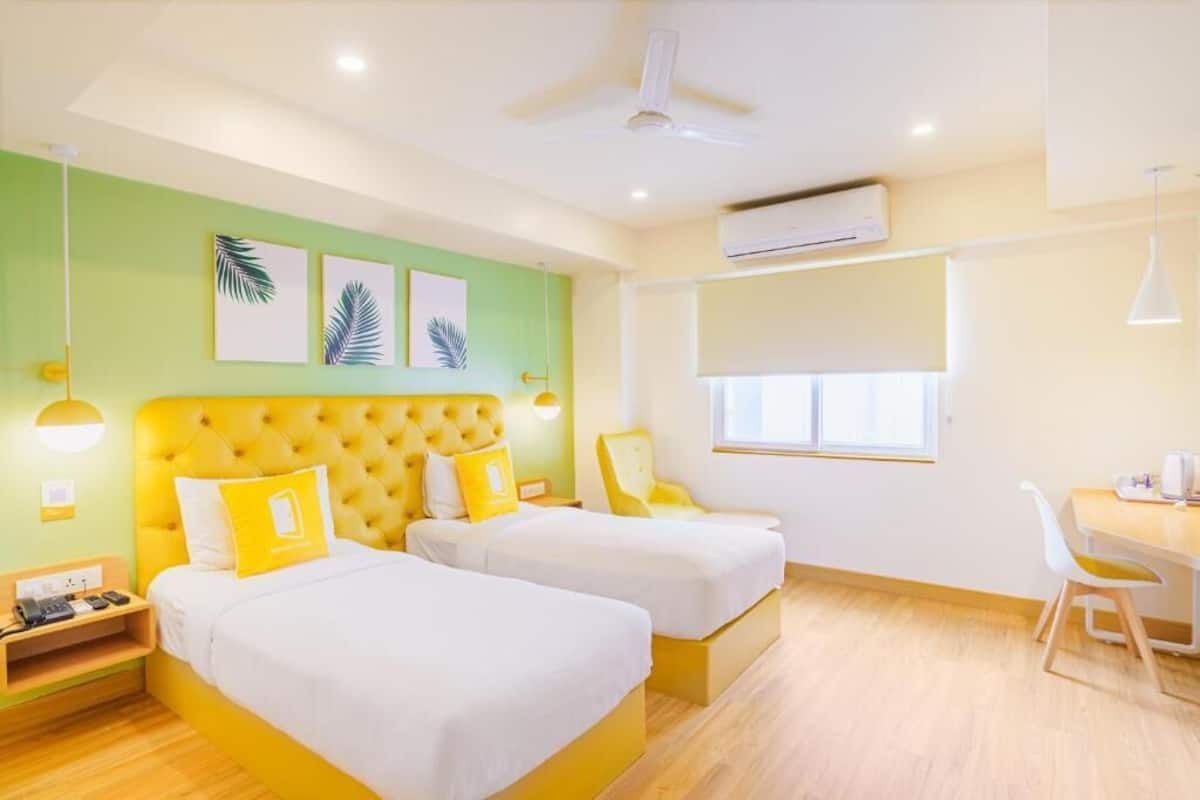 Habitación de hotel con dos camas, un escritorio, una silla y una ventana.