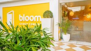 A modern building with a prominent 'bloom' sign, a potted plant, and a checkered floor pattern. - Bloom Hotel - Cyber Towers (Hyderabad)