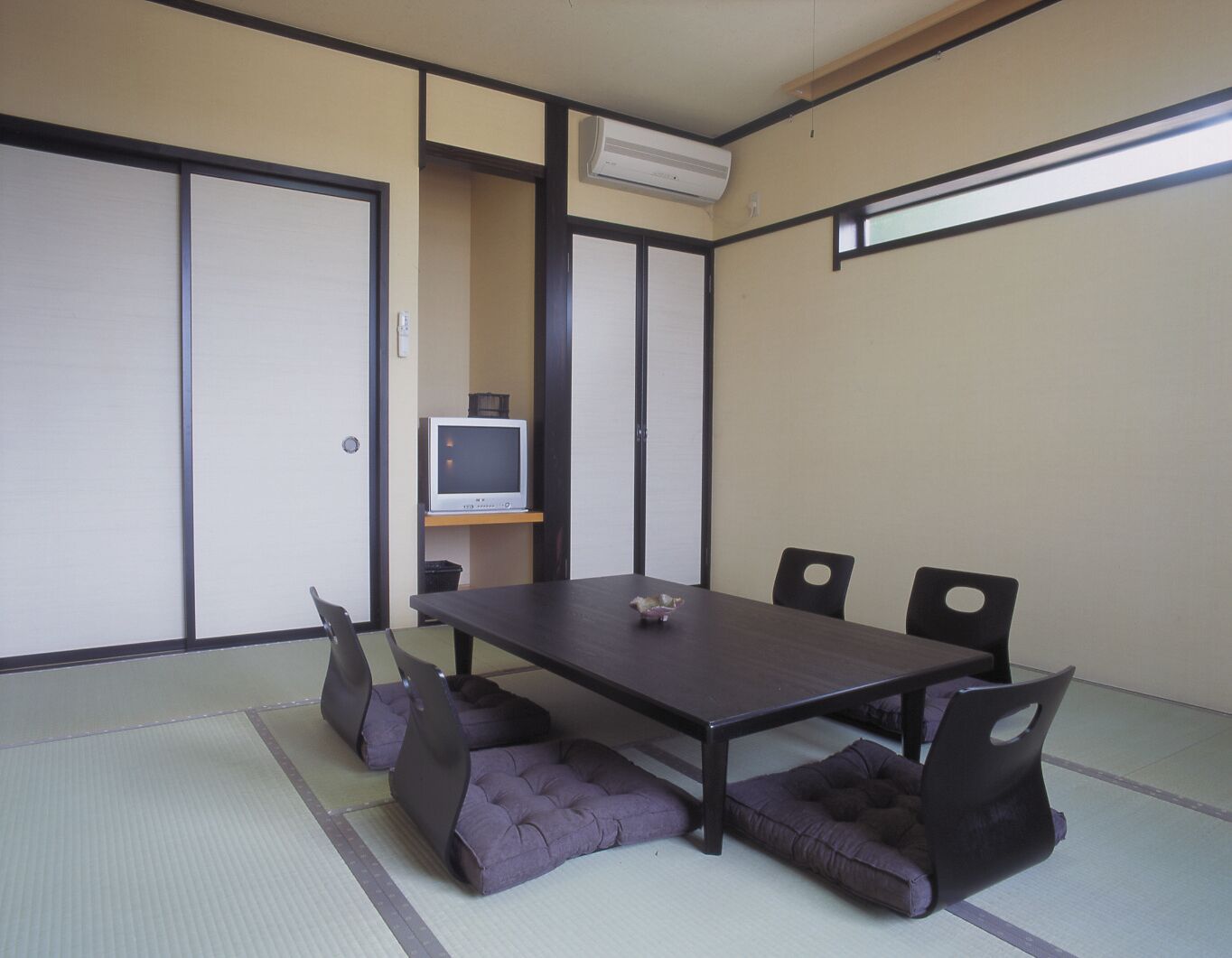 Quarto japonês tradicional com tatames, uma mesa baixa e almofadas.