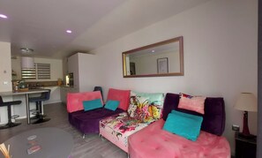 A modern living room with a sofa set, a dining area, and a kitchen in the background. - Le Petit Bonheur near the beach. (Agay)