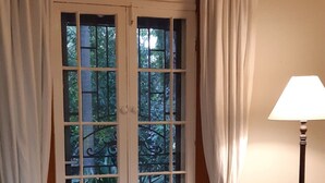 A room with a wooden table, white curtains, a chandelier, and a view through a glass door. - The Little House in the Blue Mountains (Glenbrook)