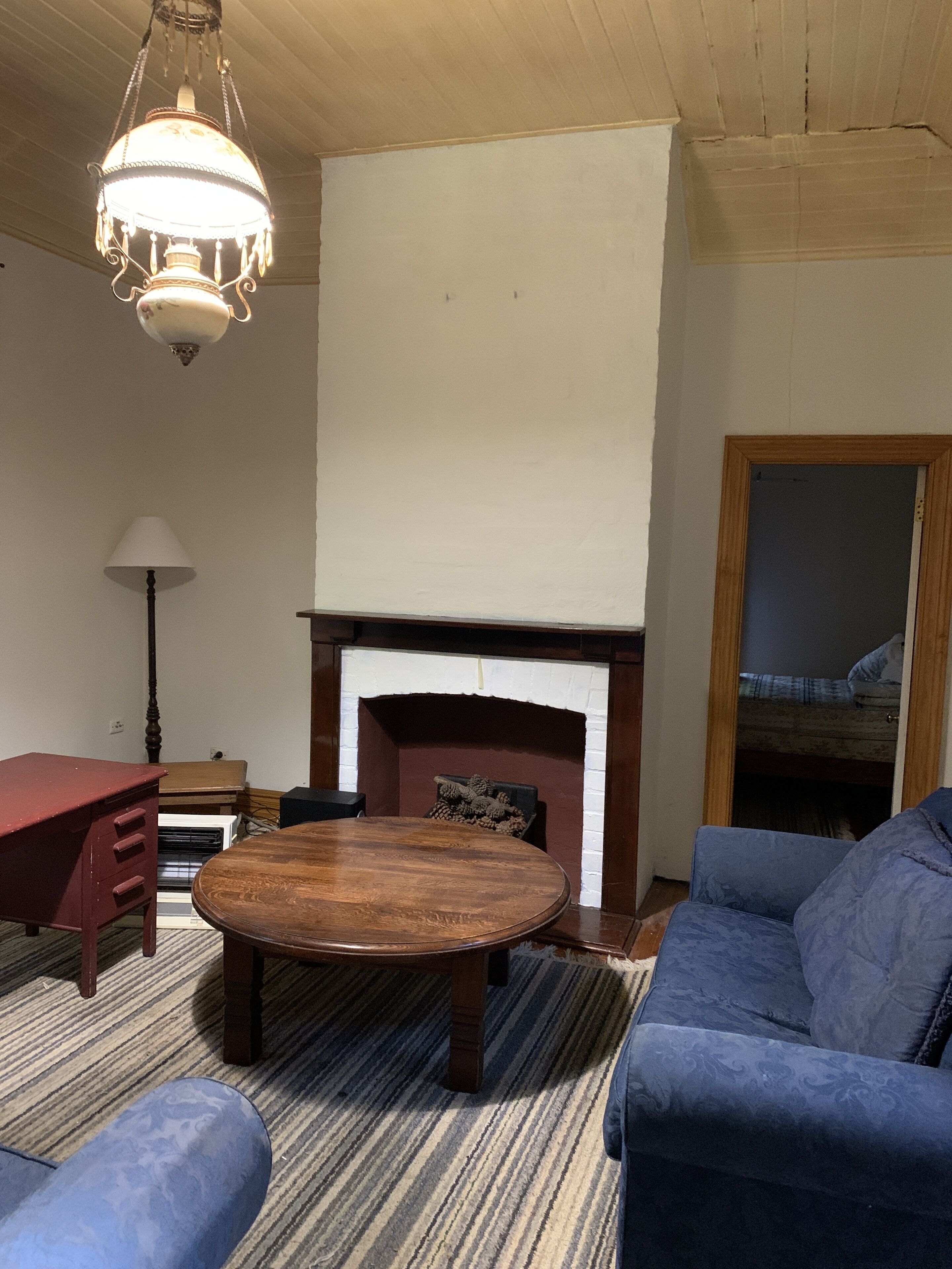 A living room with a wooden table, blue sofa, and a fireplace.