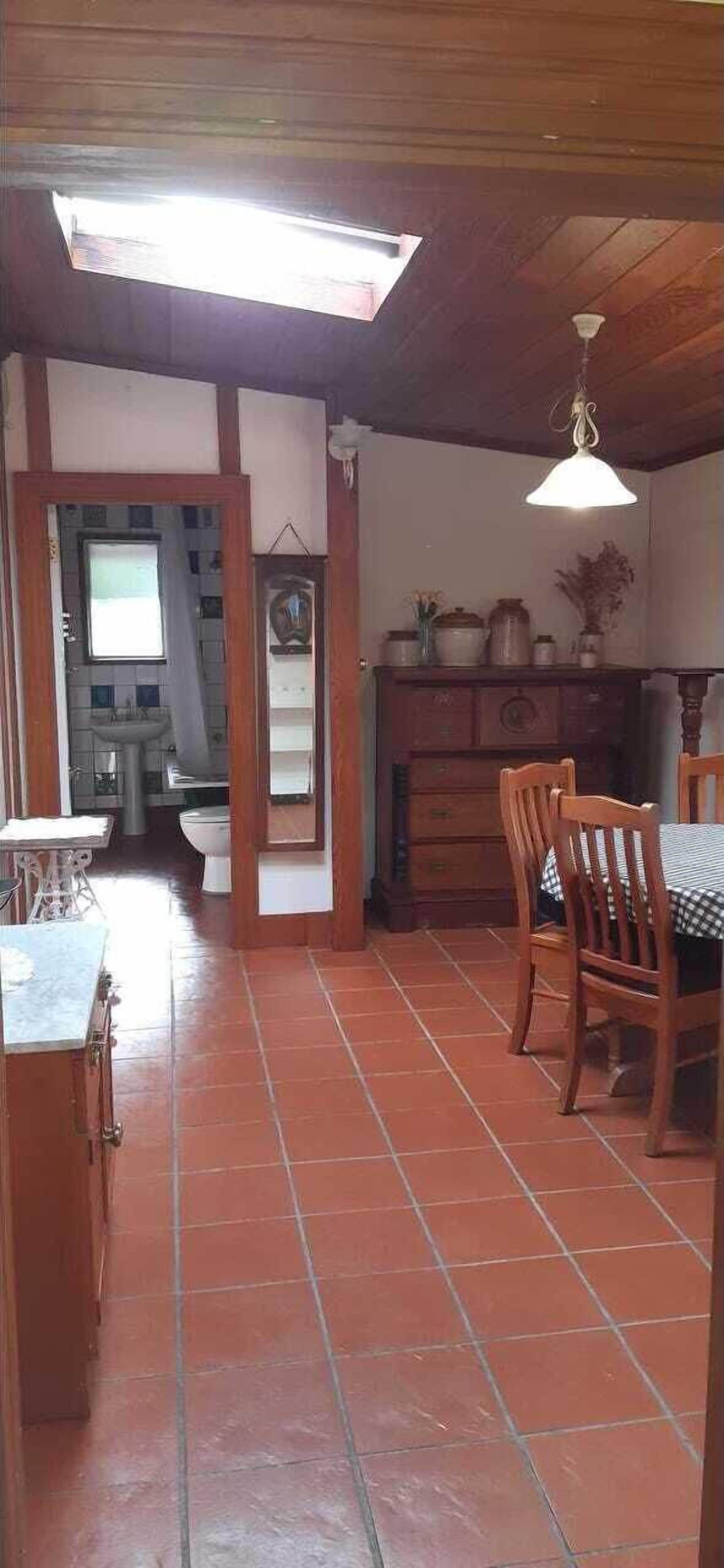 A kitchen with a dining area, wooden cabinets, a sink, and a window.
