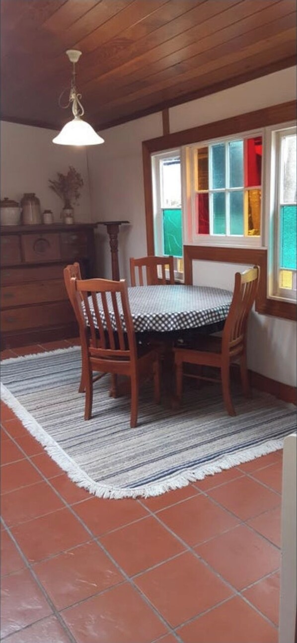 Et spiseområde med et træbord og stole, et mønstret tæppe og en loftlampe.