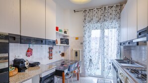 A modern kitchen with a central island, built-in appliances, and a view to the dining area. - Lodge & Art (Trieste)