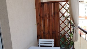A small balcony with a white table and chairs, a wooden fence, and a potted plant. - Lodge & Art (Trieste)