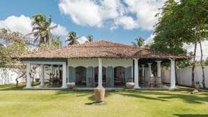 A covered outdoor area with a tiled roof, white columns, and a central stone planter. - IF Villa in Unawatuna (Unawatuna)