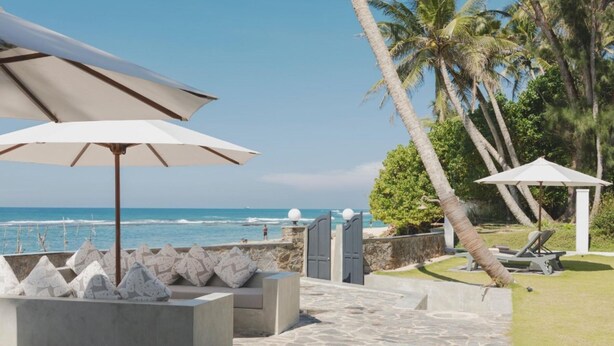 A coastal outdoor area with stone planters, umbrellas, and lounge chairs. - IF Villa in Unawatuna (Unawatuna)