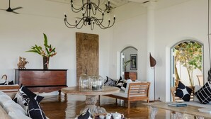 A spacious living room with a chandelier, a round coffee table, a sofa, and a wooden cabinet. - IF Villa in Unawatuna (Unawatuna)