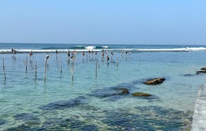 A coastal area with clear water and rocks, and people standing in the water. - IF Villa in Unawatuna (Unawatuna)