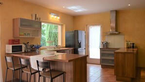Une cuisine moderne dotée d’un îlot central, d’appareils électroménagers en acier inoxydable et d’une fenêtre laissant entrer la lumière naturelle.