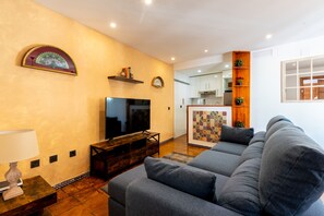 Sala de estar con sofá, televisor, mesita de madera y un adorno en la pared.