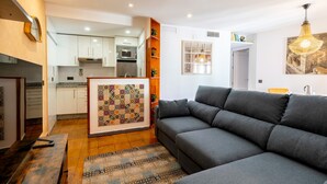 A modern living room with a grey sofa, a wooden coffee table, and a patterned rug.