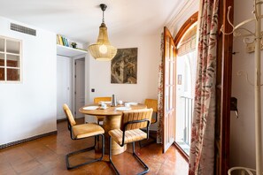 Un comedor con una mesa redonda de madera, cuatro sillas y una lámpara colgante.