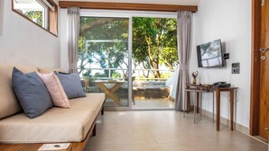 Una habitación con sofá, una mesa, televisor y puerta corrediza de vidrio que da a un espacio exterior.